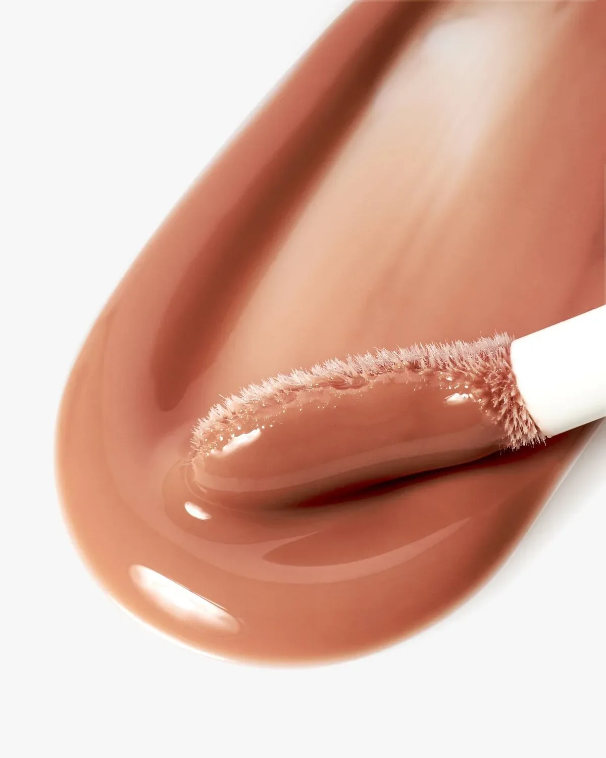 A close-up of a soft applicator in a nude gloss texture